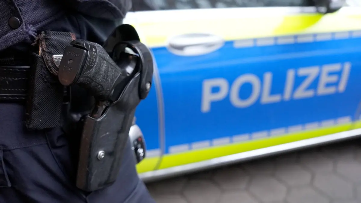 Polizeieinsatz: ARCHIV - 15.03.2024, Hamburg: Ein Polizist steht vor einem Einsatzfahrzeug der Polizei. (Symbolbild) (zu dpa: «Drei Männer überfallen Taxifahrer - mit einer Art Beil») Foto: Marcus Brandt/dpa +++ dpa-Bildfunk +++