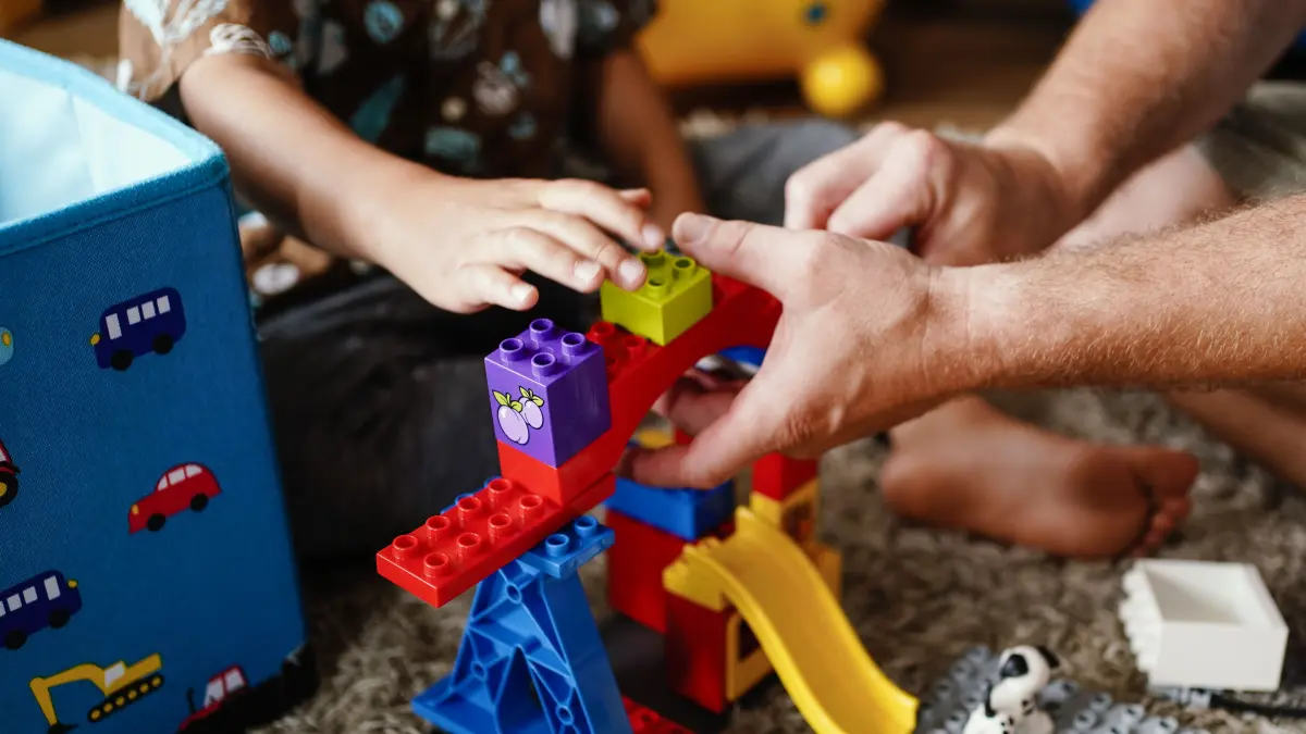 Ein Pflegevater spielt mit einem Pflegekind im Wohnzimmer. Tausende Kinder wachsen in Pflegefamilien auf. (zu dpa: ««Akuter Mangel» - In Sachsen fehlt es an Pflegefamilien») +++ dpa-Bildfunk +++