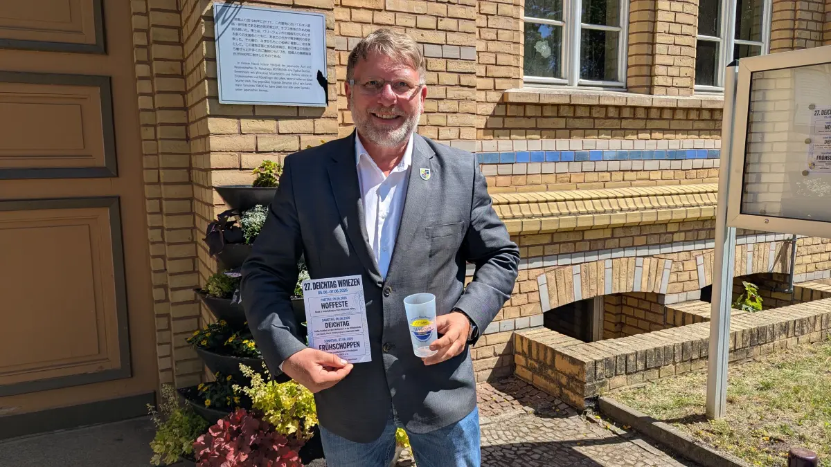 Voller Vorfreude auf das Festwochenende in Wriezen: Bürgermeister Karsten Ilm (CDU) mit Flyer und einem der Pfandbecher.