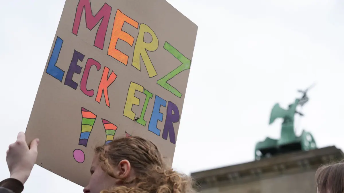 ARCHIV - 08.05.2026, Berlin: Eine Teilnehmerin einer Demonstration gegen die Wehrpflicht hält ein Plakat, auf dem steht «Merz leck Eier!!!». (zu dpa: «Jugendwort 2026: Hat «Mehrzweckeier» eine Chance?») Foto: Sven Kaeuler/dpa +++ dpa-Bildfunk +++