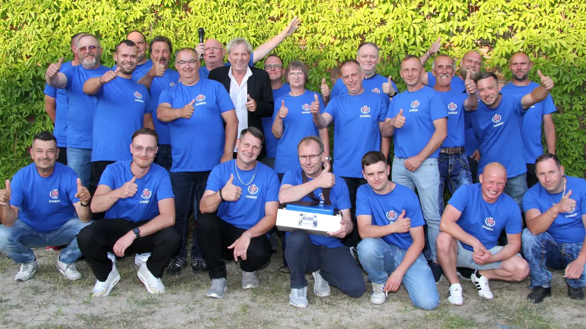 Gruppenfoto mit Schlagerstar: Dabek-Geschäftsführer Andres Klätte (hintere Reihe mit Mikrofon) aus Altglietzen bei Bad Freienwalde posiert mit Mitarbeitern und Bernhard Brink.