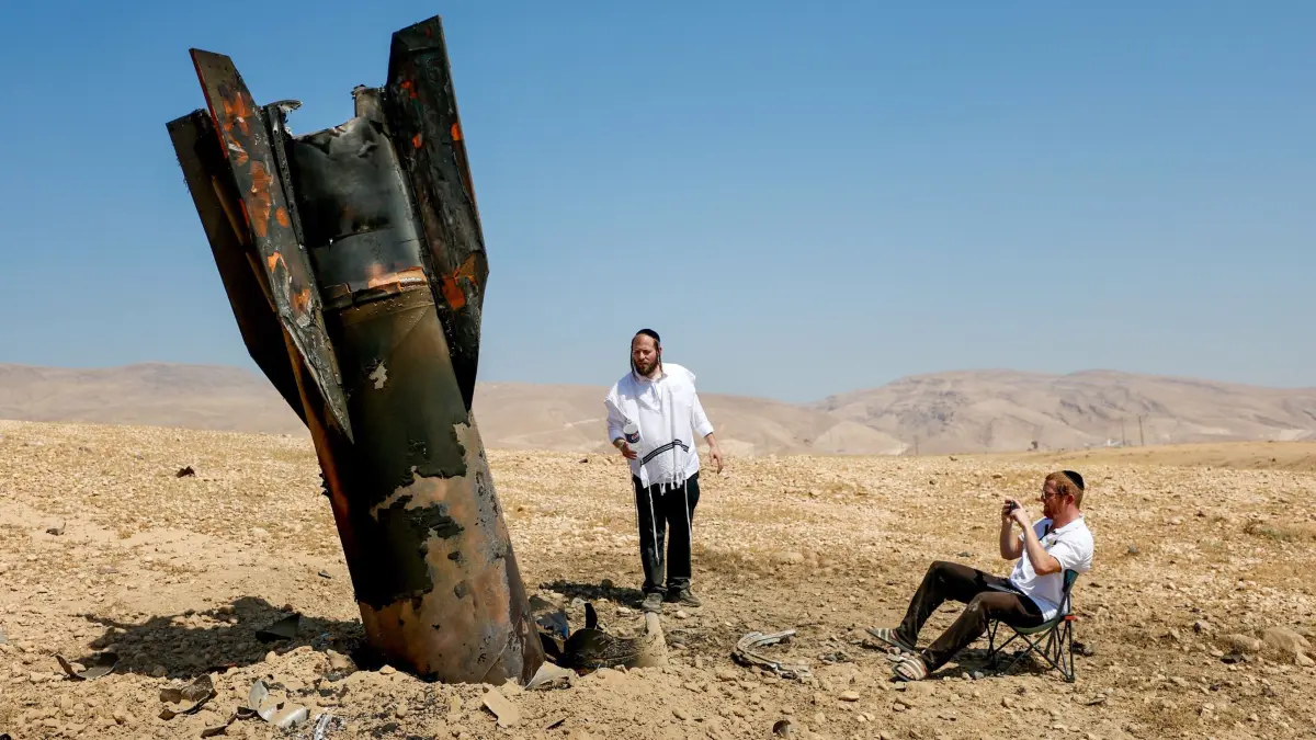 Iran-Krieg - Westjordanland: 08.06.2026, Palästinensische Gebiete, Jericho: Israelische ultraorthodoxe jüdische Männer inspizieren das Wrack einer Rakete, die nach einem iranischen Angriff nahe der Stadt Jericho im Westjordanland aus dem Boden ragt. Foto: Jamal Awad/dpa +++ dpa-Bildfunk +++