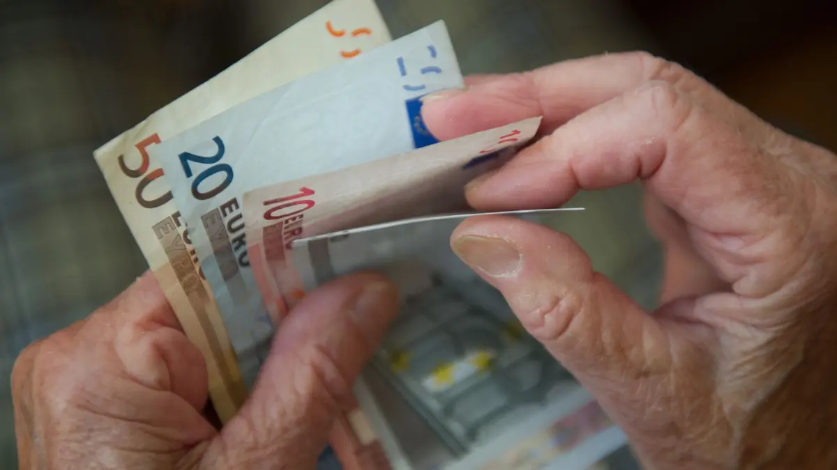 Eine Seniorin zählt Geldscheine