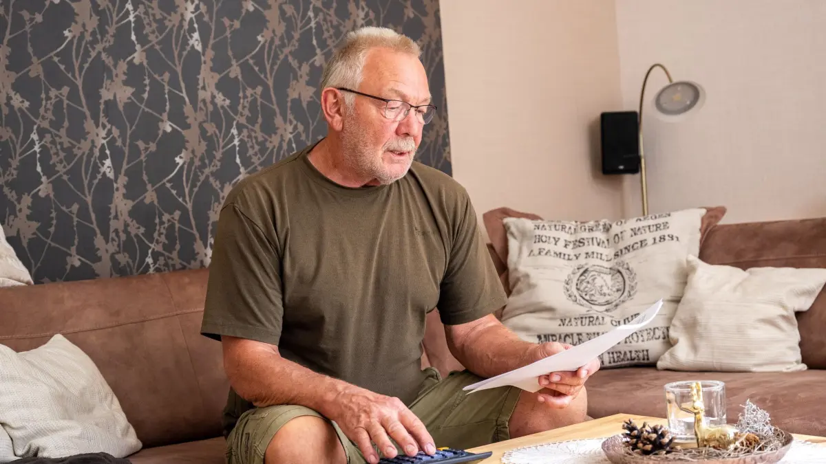 Ein älterer Mann guckt mit Taschenrechner durch Unterlagen: ILLUSTRATION - Witwenrente vor dem Aus? Die Rentenkommission denkt über ein Pflicht-Splitting nach. Klingt gerecht – kann aber für Hinterbliebene finanziell schlechter sein als die Witwenrente. (zu dpa: «Witwenrenten-Aus? Wie sich das finanziell auswirken könnte») Foto: Benjamin Nolte/dpa-mag - Honorarfrei nur für Bezieher des Dienstes dpa-Magazin +++ dpa-Magazin +++
