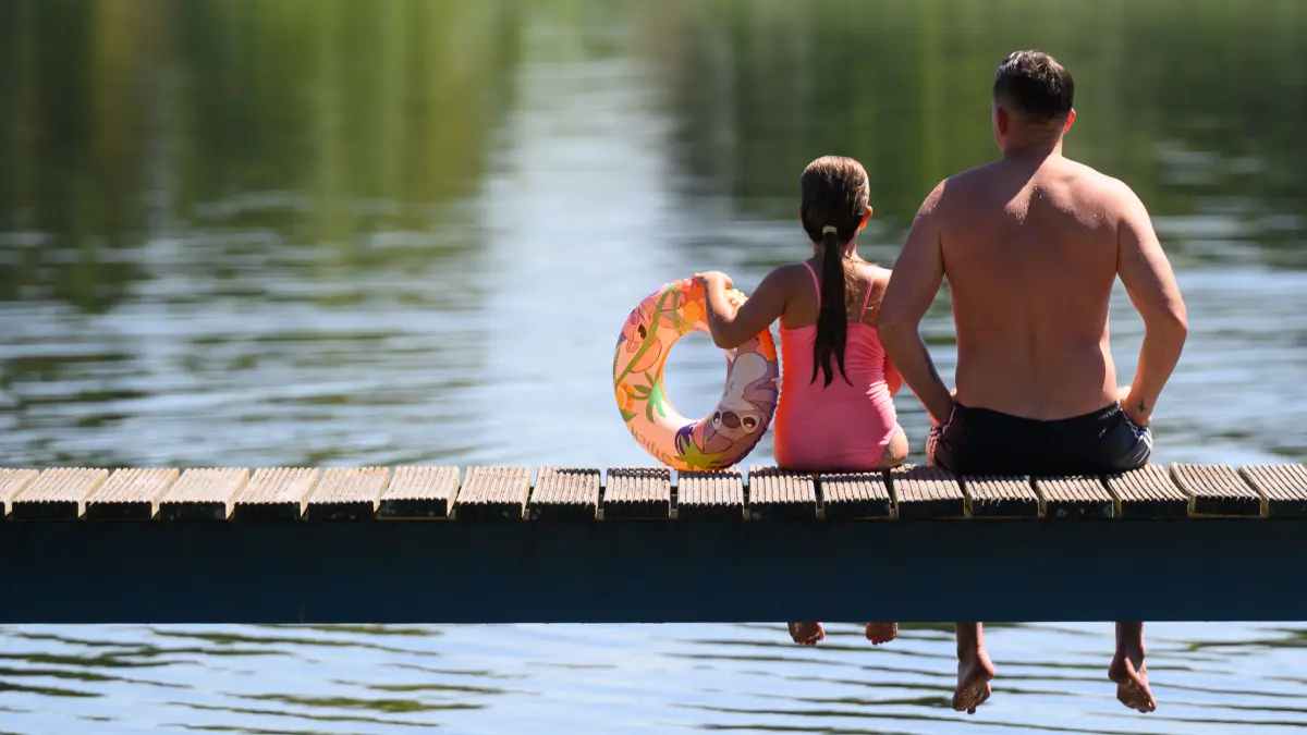 Ein Vater und seine Tochter sitzen auf einem Steg am Strandbad am Großen Müllroser See. Der Deutsche Wetterdienst (DWD) erwartet am Mittwoch (02.07.2025) Temperaturen nahe der 40-Grad-Marke. Doch die Abkühlung lässt laut DWD nicht lange auf sich warten. +++ dpa-Bildfunk +++
