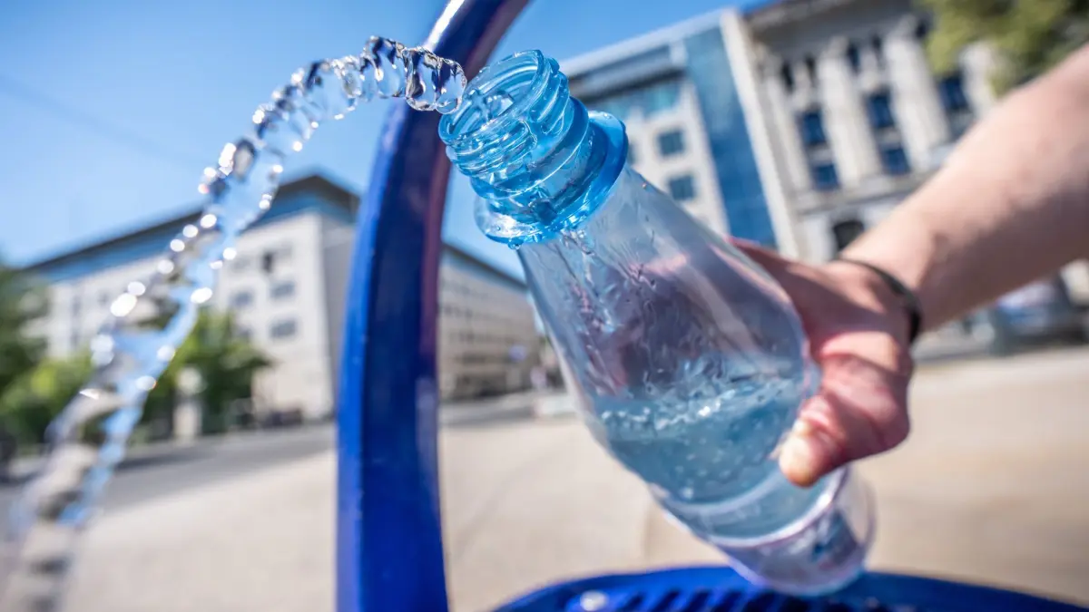Hitze in Deutschland - Berlin: ARCHIV - 02.07.2025, Berlin: Ein Mann füllt seine Wasserflasche am öffentlichen Wasserspender unter den Linden. Hitze und Temperaturen von mehr als 30 Grad werden in der Hauptstadt erwartet. (zu dpa: «Ohne Rückzugsort - Wie Obdachlose bei Hitze Hilfe bekommen») Foto: Michael Kappeler/dpa +++ dpa-Bildfunk +++
