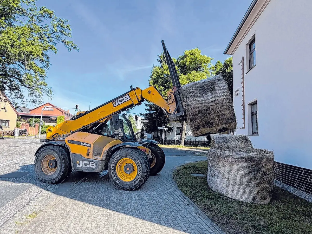 Bevor die Strohbiene über dem Festgeschehen wacht, ist Präzisionsarbeit gefragt: Mit einem Teleskoplader werden die Strohballen für die beliebte Figur in Position gebracht.