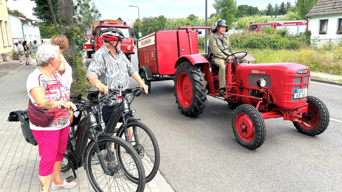 Festumzug durch Tornow: Auch Doris und Wolfgang Gora aus Sommerfelde schauen, auf ihre Fahrräder gestützt, mit Interesse zu, wie die Fahrzeugtechnik mehrerer Jahrzehnte durch den dörflichen Ortsteil von Eberswalde rollt.