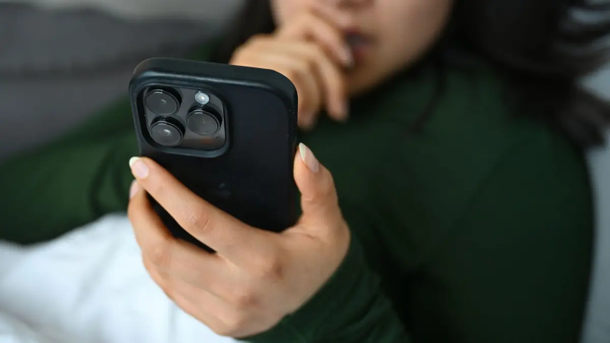 Eine junge Frau liegt mit ihrem Handy auf der Couch: ILLUSTRATION - 01.04.2026, Berlin: Die Thüringer Polizei weitet ihre digitale Kommunikation aus und ist ab sofort auf WhatsApp erreichbar. (Foto: Archiv) (zu dpa: «Polizei Thüringen informiert jetzt über Messenger-Dienst») Foto: Elisa Schu/dpa/dpa-tmn +++ dpa-Bildfunk +++