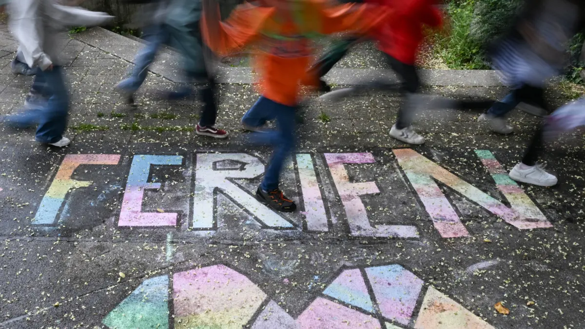 Schüler einer Grundschule laufen am letzten Schultag vor den Sommerferien in Baden-Württemberg über einen bunten Kreide-Schriftzug «Ferien» (Wischeffekt durch Langzeitbelichtung). +++ dpa-Bildfunk +++