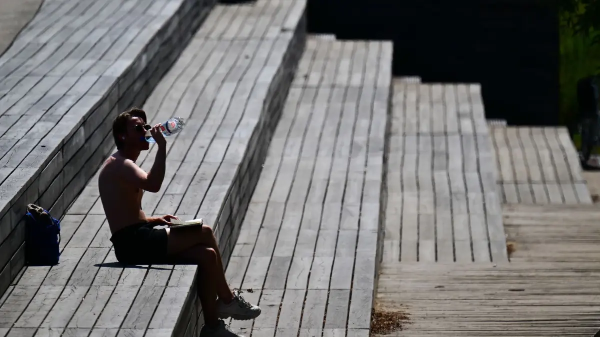 Hitze in Berlin: 23.06.2026, Berlin: Ein Mann sitzt im Park am Gleisdreieck in der Sonne und trinkt Wasser. Foto: Sebastian Gollnow/dpa +++ dpa-Bildfunk +++