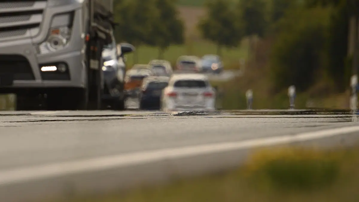 Sogenanntes Hitzeflimmern ist auf einer befahrenen Straße zu sehen. Die Sonne kann den Asphalt auf bis zu 60 Grad Celsius erhitzen. Das ist in mehrfacher Hinsicht gefährlich.
