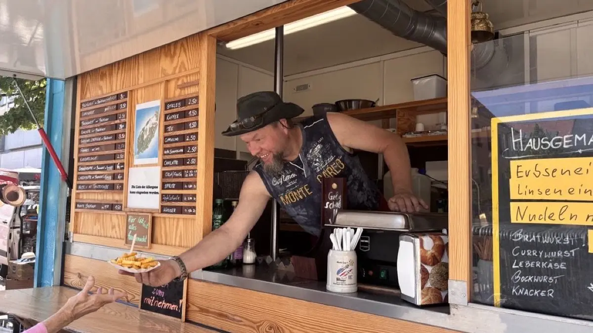 Händler Marco Plath verkauft an diesem Tag deutlich weniger Essen als sonst. Eine ältere Dame entscheidet sich bei über 30 Grad dennoch, eine Pommes zu essen.