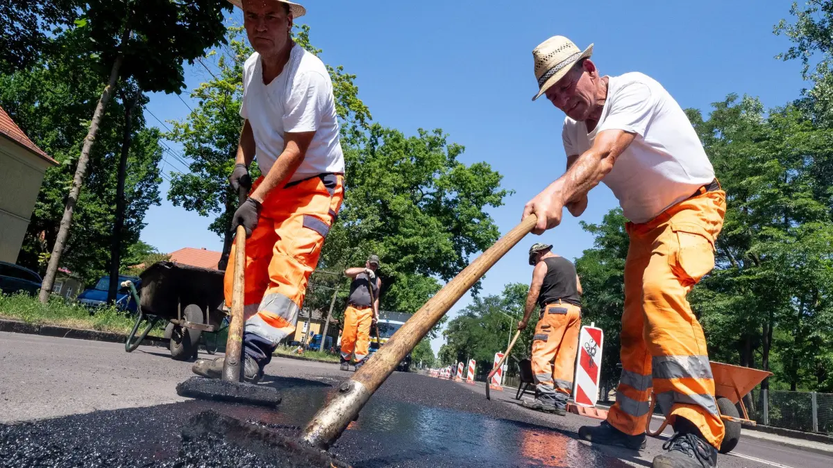 Hitze in Potsdam: 25.06.2026, Brandenburg, Potsdam: Asphaltbauer belegen bei 33 Grad in der Mittagssonne in Potsdam eine Straße mit 210 Grad heißem Gussasphalt. Foto: Georg Moritz/dpa +++ dpa-Bildfunk +++