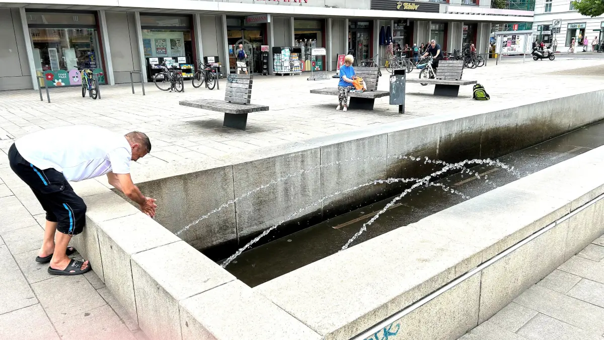 Erfrischung in Eberswalde: Am Brunnen auf dem Marktplatz benetzt ein Passant seine Hände mit Wasser und sorgt auf diese Weise für eine willkommene Abkühlung. Wo wird so etwas sonst noch ermöglicht?