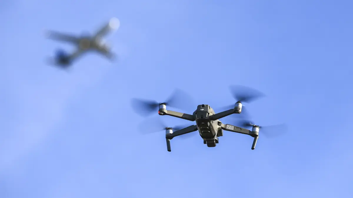 Eine Drohne fliegt vor einem startenden Flugzeug. Störungen durch die unbemannten Flugobjekte haben in diesem Jahr stark zugenommen. Polizei und Flugsicherung reagieren. (Symbolbild)