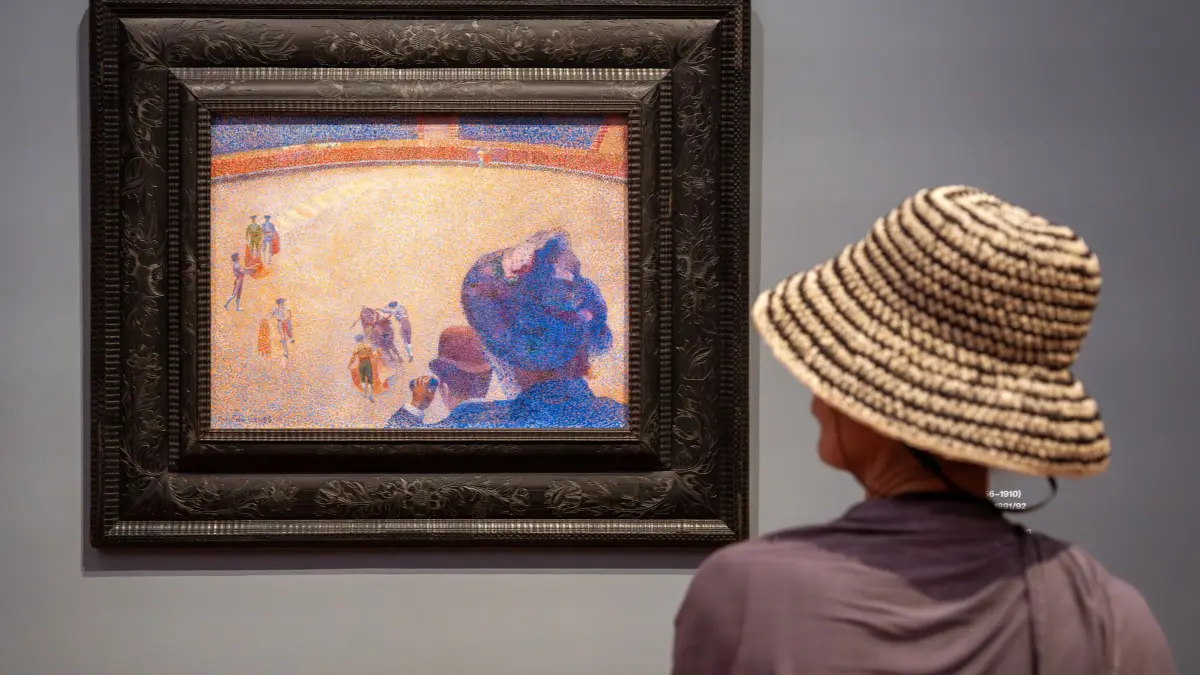 Paul-Signac-Ausstellung im Museum Barberini: 02.07.2026, Brandenburg, Potsdam: Eine Frau betrachtet während der Presse-Vorbesichtigung der Ausstellung «Symphonie der Farben. Paul Signac und der Neoimpressionismus» das Bild „Stierkampf“, 1891/1892, Öl auf Leinwand) des Künstlers Henri-Edmond Cross. Die Ausstellung ist bis zum 11.10.2026 zu sehen. Foto: Soeren Stache/dpa - ACHTUNG: Nur zur redaktionellen Verwendung im Zusammenhang mit dem genannten Text +++ dpa-Bildfunk +++