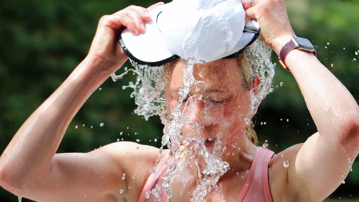 Hamburger Halbmarathon: ARCHIV - 25.06.2022, Hamburg, AuĂźenalster: Halbmarathon, Hamburg. Eine Teilnehmerin füllt an einer Erfrischungsstation ihre Mütze mit Wasser und kippt sich diese über den Kopf. Erneut hatten Teilnehmer und Veranstalter beim größten Halbmarathon in Hamburg mit hohen Temperaturen zu kämpfen. (zu «Hamburger Halbmarathon: Diesmal weniger Hilfseinsätze wegen Hitze») (zu dpa: «Halbmarathon in Hamburg wird am 25. Oktober nachgeholt») Foto: Markus Tischler/dpa +++ dpa-Bildfunk +++