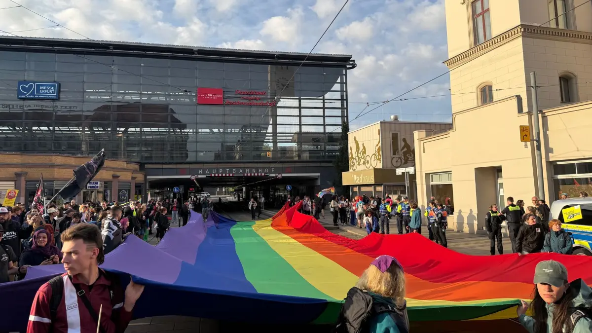 Bundesparteitag der AfD: 04.07.2026, Thüringen, Erfurt: Demonstranten gegen den AfD-Bundesparteitag halten eine riesige Regenbogenflagge vor dem Hauptbahnhof Erfurt. Der Bundesparteitag der AfD findet am 4. und 5. Juli in der Messe Erfurt statt. Foto: Stefan Hantzschmann/dpa +++ dpa-Bildfunk +++
