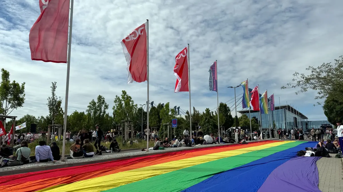Bundesparteitag der AfD: 04.07.2026, Thüringen, Erfurt: Eine übergroße Regenbogenfahne liegt ausgebreitet neben einer Kundgebung des DGB auf dem Boden in der Nähe der Messehalle. Der Bundesparteitag der AfD findet am 4. und 5. Juli findet in der Messe Erfurt statt. Foto: Sarah Knorr/dpa +++ dpa-Bildfunk +++