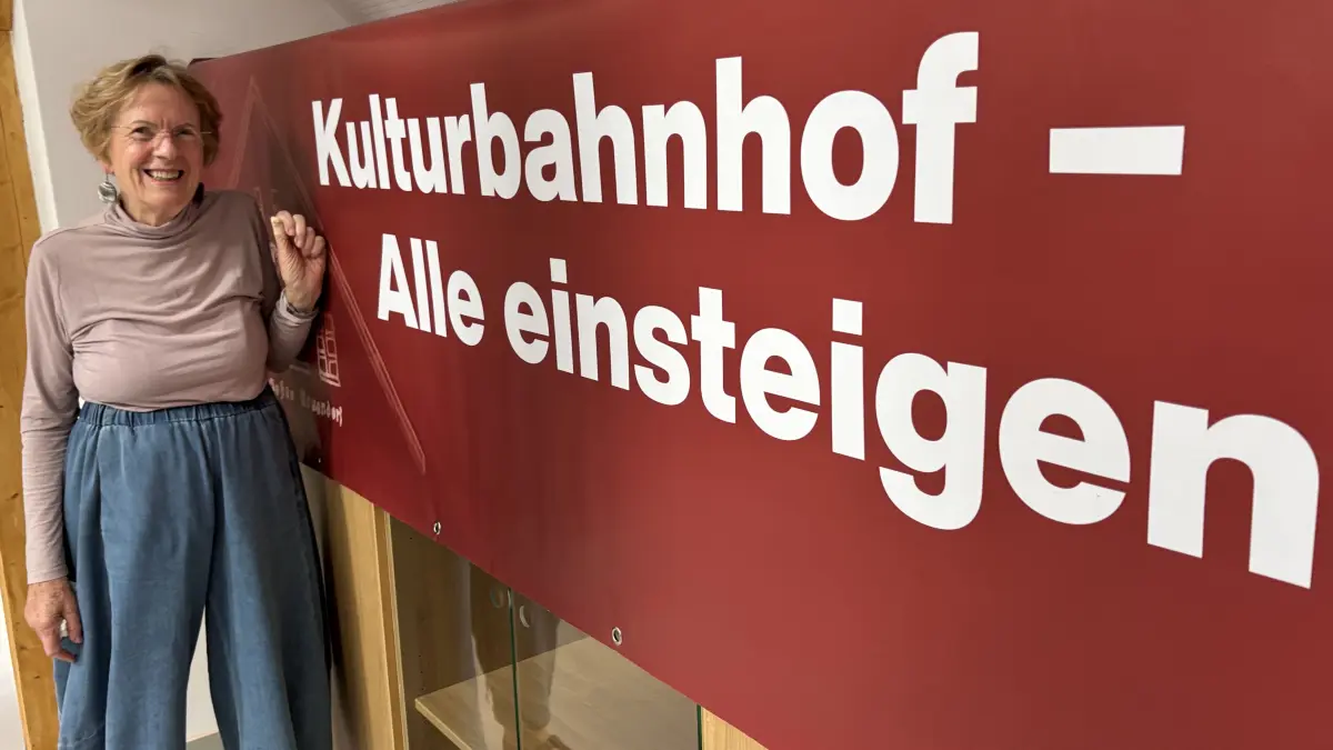 Kämpferin am Ziel: Brigitte Tham hat sich jahrelang für die Idee Kulturbahnhof eingesetzt. Hier steht sie neben einem Plakat, mit dem sie gegen die Verzögerungen beim Prestigeprojekt protestiert hatte. Es ist im Kulturbahnhof ausgestellt.