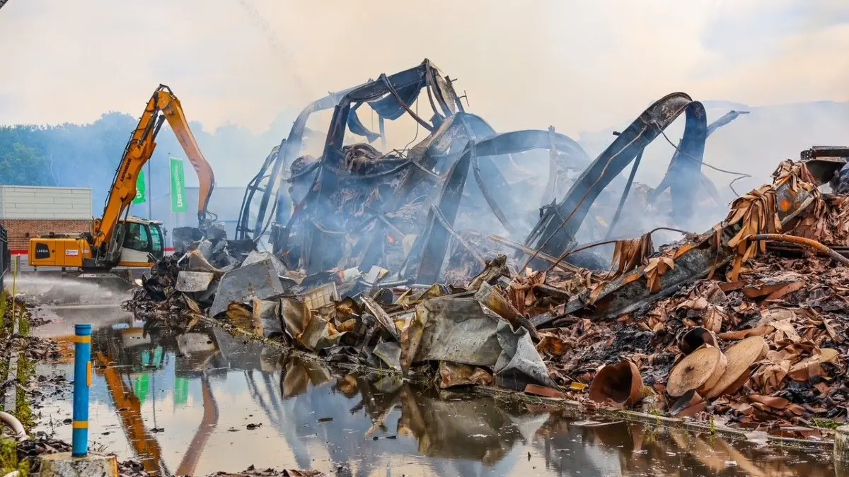 Die Löscharbeiten im Gewerbegebiet in Oranienburg-Süd dauern am Montag (6. Juli) an. Bagger und Radlader ziehen die Glutnester auseinander, damit die Feuerwehr besser löschen kann.