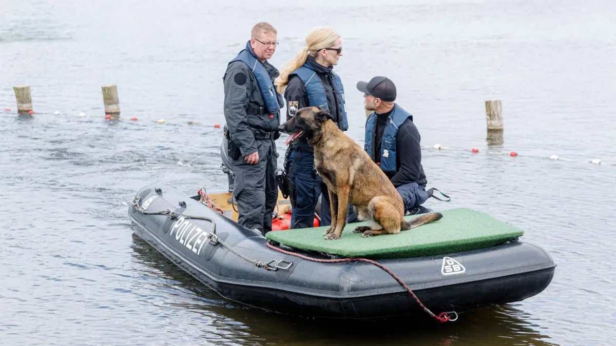 Polizei sucht am Westensee nach einer vermissten Frau: ARCHIV - 21.05.2025, Schleswig-Holstein, Westensee: Einsatzkräfte kehren mit einem Spürhund an das Ufer des Westensees zurück, auf dem sie nach einer vermissten Frau aus Noer gesucht haben. (zu dpa: «Anklage im Fall der vermissten Frau aus Noer») Foto: Markus Scholz/dpa +++ dpa-Bildfunk +++