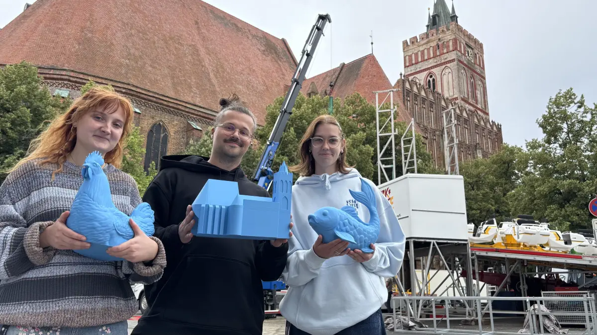 Projektleitungstrio für das Stadtfest Bunter Hering in Frankfurt (Oder): Gene Flatau, Gregor Sündermann und Lena-Marie Gläßer zeigen die Frankfurt-Wahrzeichen, die per 3D-Drucker für das Minigolfspiel erstellt wurden.