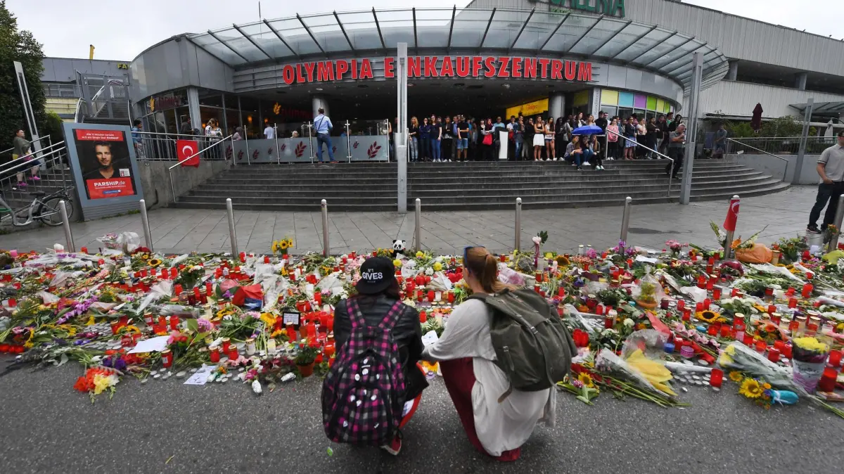 Münchner OEZ-Attentat: ARCHIV - 25.07.2016, Bayern, München: Blumen und Kerzen liegen vor dem Haupteingang des Olympia-Einkaufszentrums (OEZ). Drei Tage zuvor hatte dort ein 18-Jähriger neun Menschen erschossen und sich danach selbst getötet. (zu dpa: «Zehn Jahre nach Münchner Anschlag: Die Wut trauernder Eltern») Foto: Peter Kneffel/dpa +++ dpa-Bildfunk +++