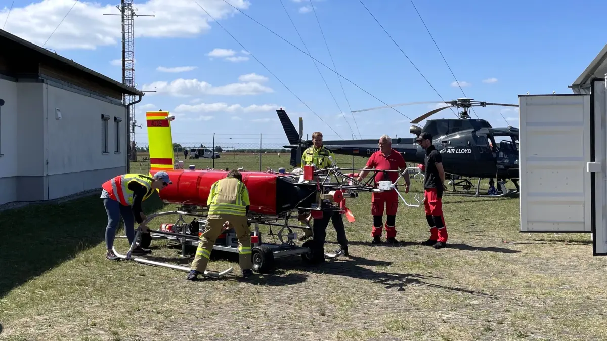 Startvorbereitungen auf dem Messfeld Falkenberg des DWD-Observatoriums Lindenberg: Diese mit Messtechnik bestückte Schleppsonde von Tropos bringt Pilot Jürgen Schütz (2. von rechts) mit dem Helikopter in die Wolken über Tauche.