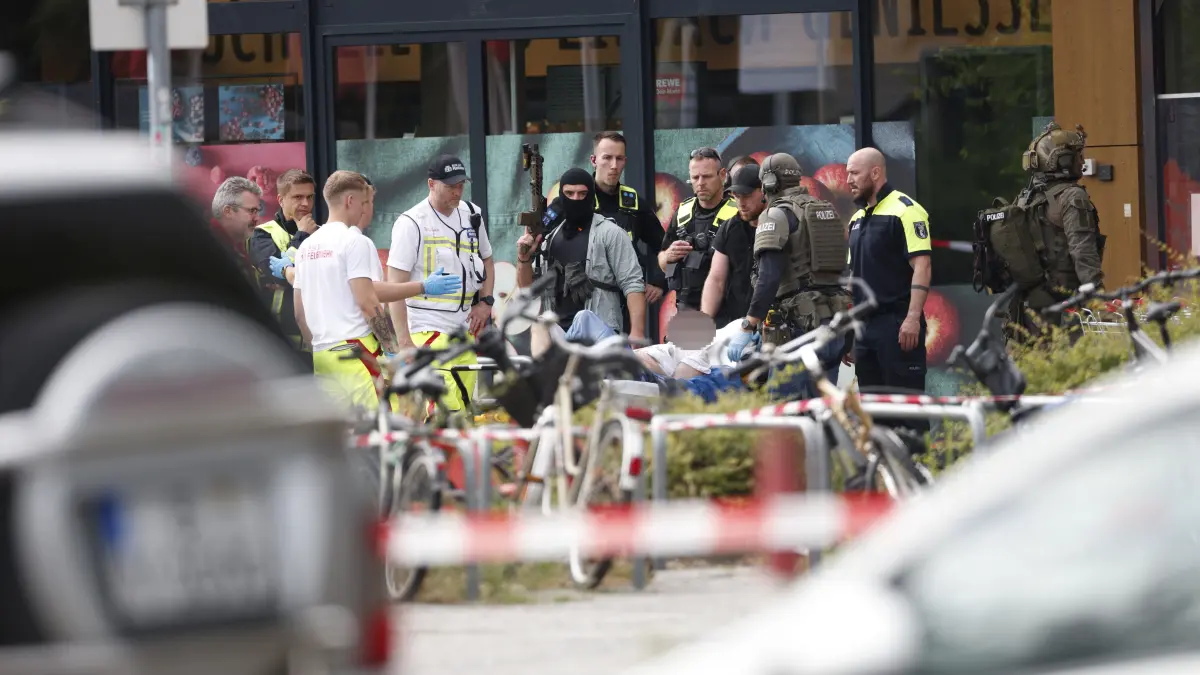 Einsatzkräfte stehen vor einem Supermarkt neben einer verletzten Person auf einer Trage. In dem Supermarkt im Süden Berlins hielt ein Mann seit dem späten Freitagabend (10.07.2026) eine Frau als Geisel. Die Geiselnahme wurde durch die Polizei beendet.