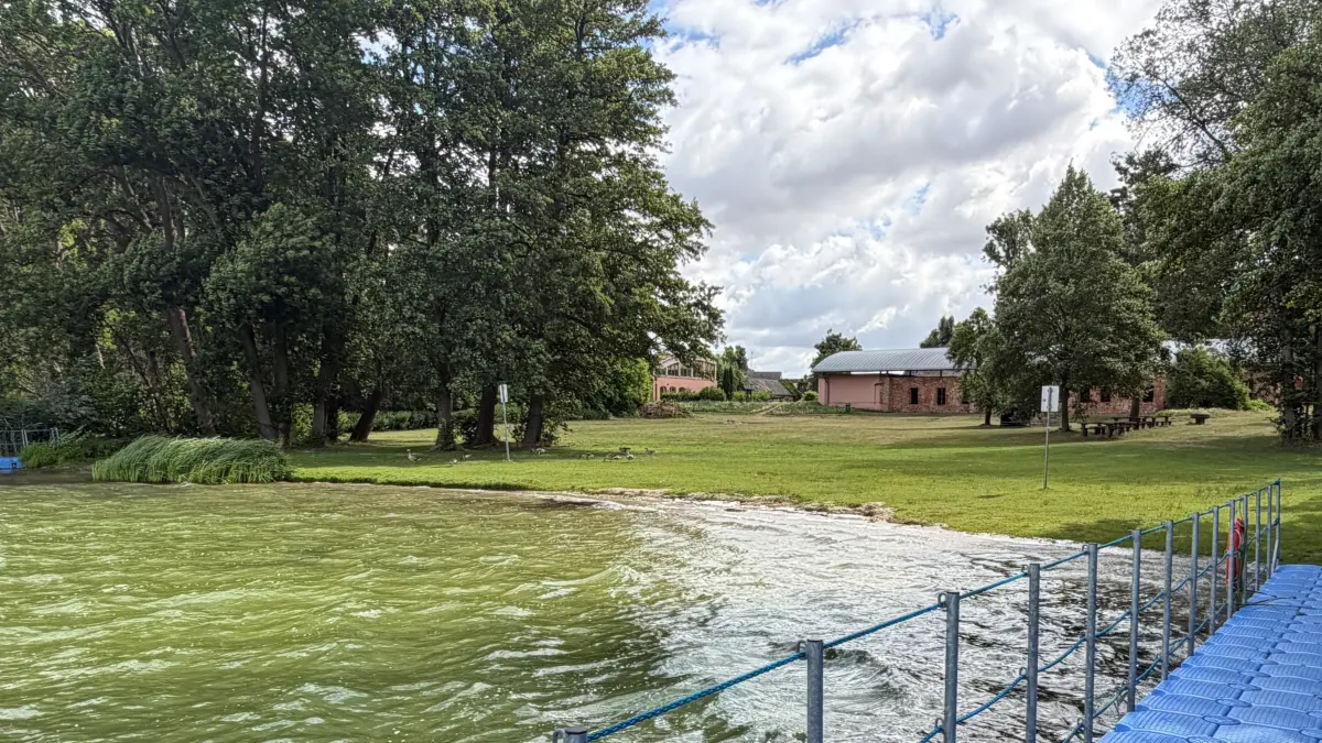 Der Klostersee in Altfriedland bietet beste Voraussetzungen für einen entspannten Sommertag. Hinter der großen Liegewiese sind Klosterruine und Klosterschänke zu sehen – doch in diesem Sommer ist etwas anders als gewohnt.