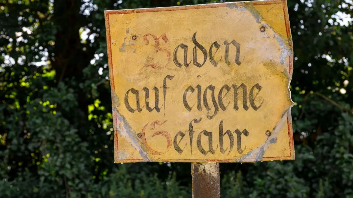Wetter in Bayern: 12.07.2026, Bayern, Lichtenfels: Auf einem Schild am Badesee Reundorf steht „Baden auf eigene Gefahr“. Foto: Daniel Vogl/dpa +++ dpa-Bildfunk +++