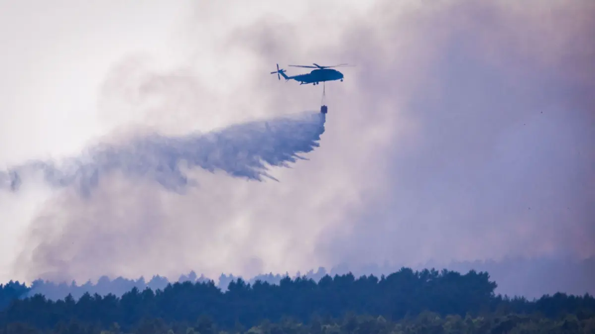Waldbrand im Müritz-Nationalpark: 16.07.2026, Mecklenburg-Vorpommern, Kratzeburg: Ein Bundeswehr-Hubschrauber CH-53 wirft aus dem 5000-Liter-Tank Löschwasser über dem Waldbrand im Müritz-Nationalpark ab. Der Großbrand auf einem ehemaligen Truppenübungsgelände hat sich auf mittlerweile 269 Hektar ausgedehnt. Derzeit sind etwa 375 Einsatzkräfte vor Ort. Foto: Jens Büttner/dpa +++ dpa-Bildfunk +++