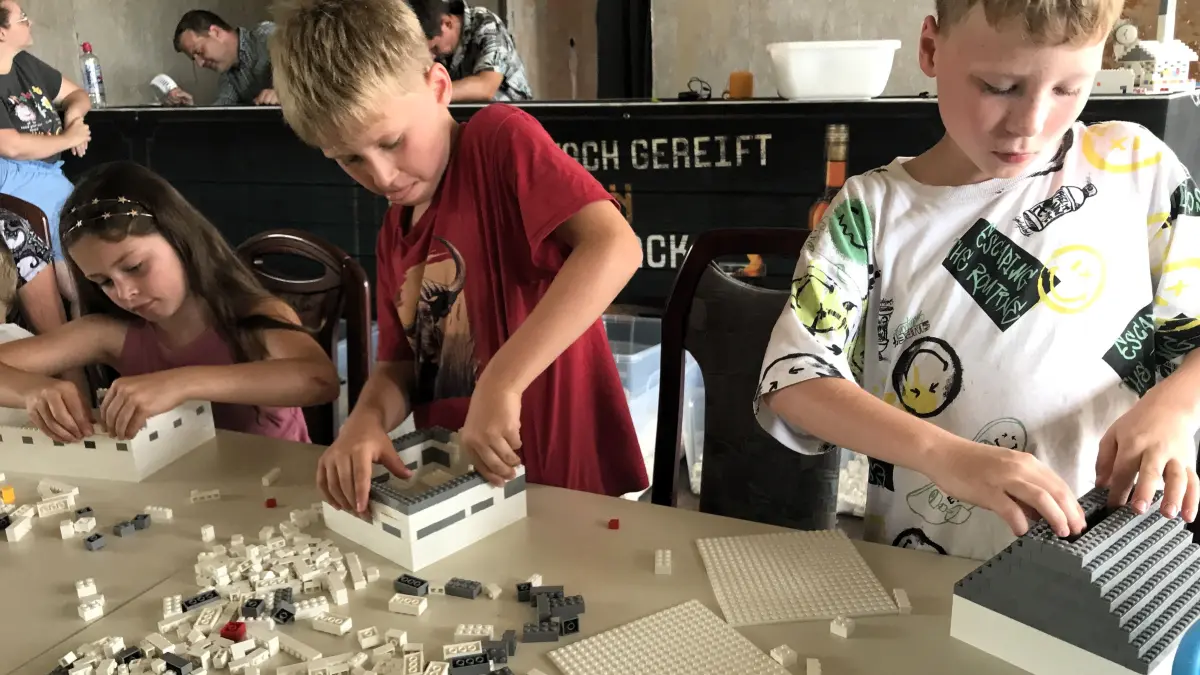 Aktion „Meet’n’Build“ am 17. Juli 2026 in Eisenhüttenstadt. Sina Müller (10), Luca Kucklick (8) und Theo Kucklick (8, v.l.) bauen an ihren Projekten. Foto: Frank Groneberg
