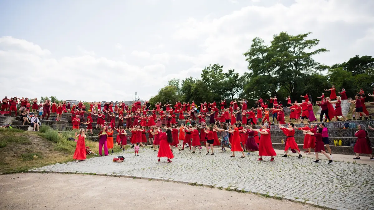 Tanzaktion „Wuthering Heights Day“: 18.07.2026, Berlin: Teilnehmer tanzen bei der Tanzaktion «Wuthering Heights Day» im Görlitzer Park. «Wuthering Heights Day» ist eine weltweite Tanzaktion, bei der Menschen in roten Kleidern die Choreographie aus dem Musikvideo von Kate Bushs Song «Wuthering Heights» aus dem Jahr 1978 nach tanzen. Foto: Christoph Soeder/dpa +++ dpa-Bildfunk +++