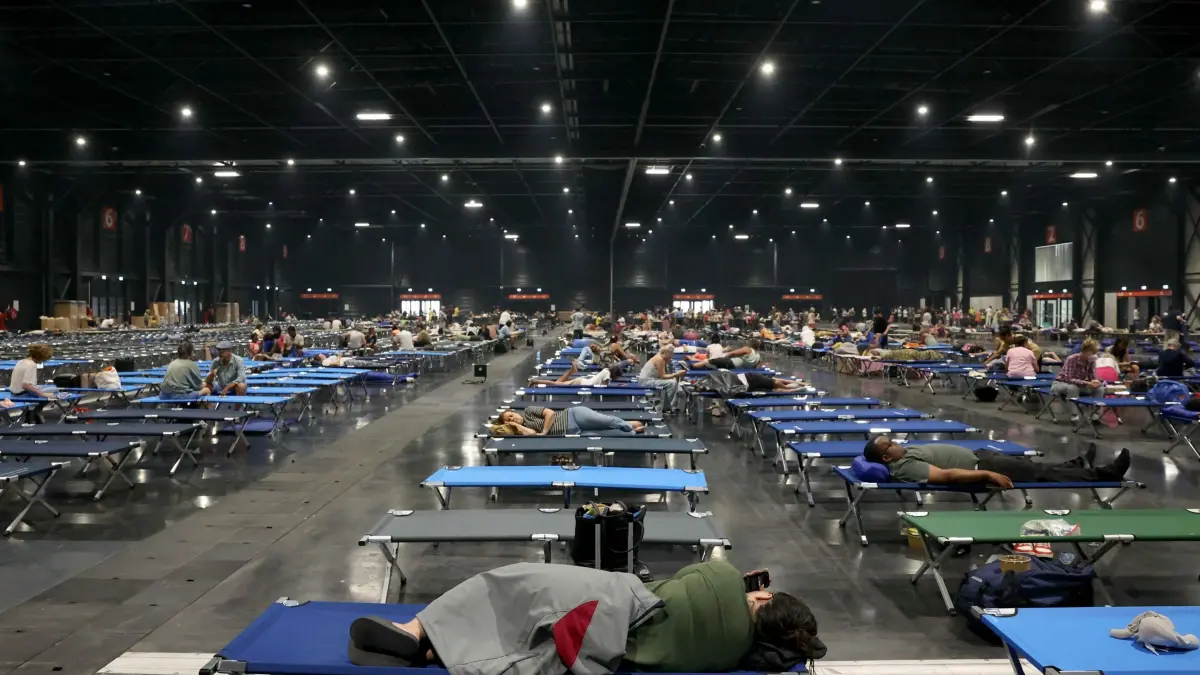 Brände in Frankreich: 25.07.2026, Frankreich, Bordeaux: Anwohner ruhen sich im Parc des Expositions de Bordeaux aus, nachdem sie aufgrund von Waldbränden in der Region aus der Gefahrenzone gebracht worden sind. In Frankreich und Spanien wurden mehr als 160.000 Menschen aus Waldbrandgebiete in der Nähe von Madrid und Bordeaux gebracht. Foto: Alain Jocard/AFP/dpa +++ dpa-Bildfunk +++