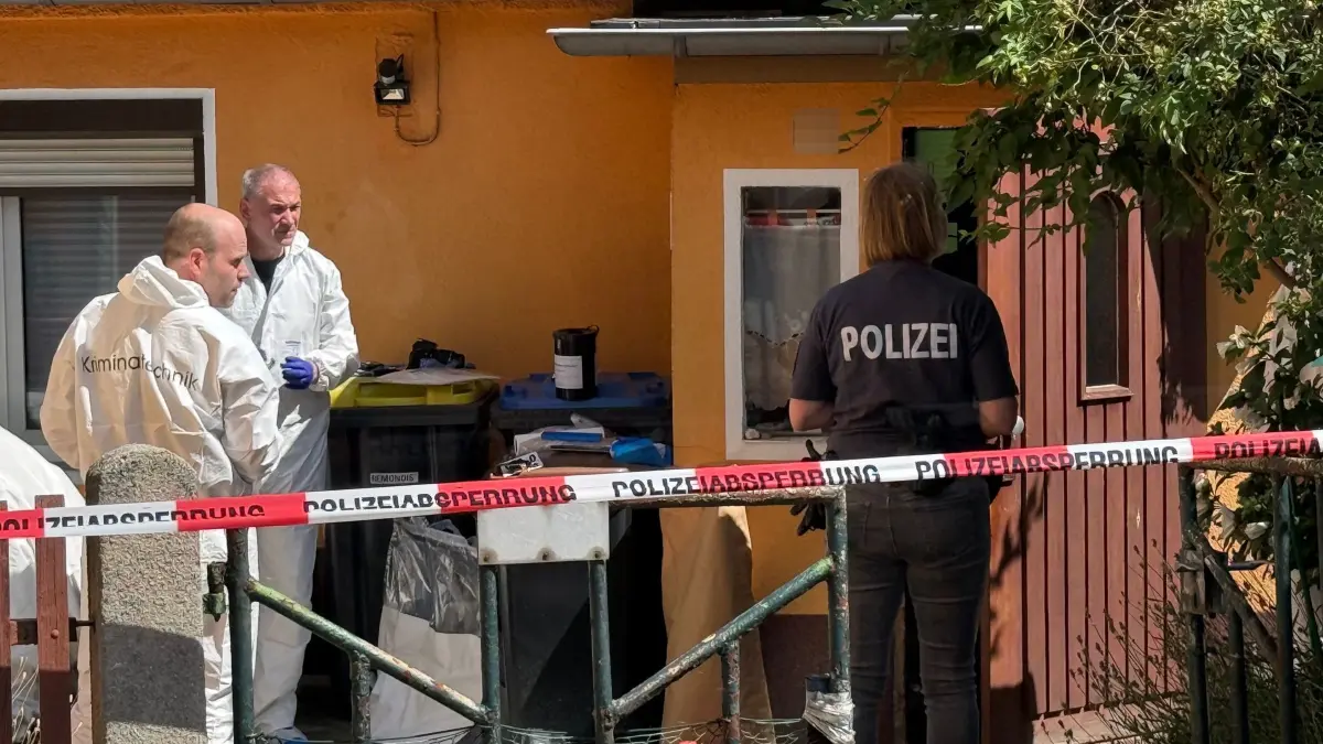 Fund von zwei Toten in Südbrandenburg: 25.07.2026, Brandenburg, Ortrand: Mitarbeiter der Kriminaltechnik und Polizei stehen vor einem Haus. Ermittler fanden in der Stadt im Landkreis Oberspreewald-Lausitz die Leichen eines 57 Jahre alten Mannes und einer 45-jährigen Frau. Eine schwer verletzte Person sei ins Krankenhaus gekommen. Foto: Andreas Richter/dpa +++ dpa-Bildfunk +++