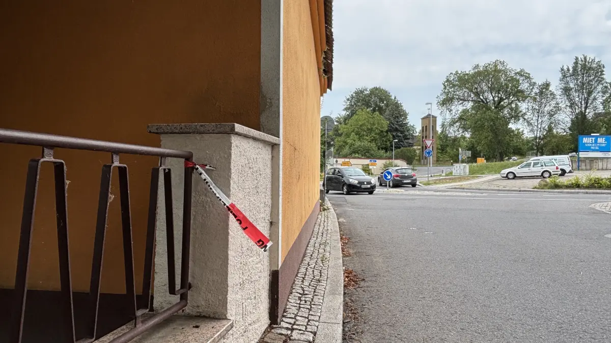 Ein Rest der rot-weißen Polizeiabsperrung deutete auf den Großeinsatz der Polizei hin, der jüngst in Ortrand stattgefunden hat. Nach dem Fund zweier Leichen im Nebengebäude auf einem Eckgrundstück sind die Menschen in Ortrand noch immer fassungslos.