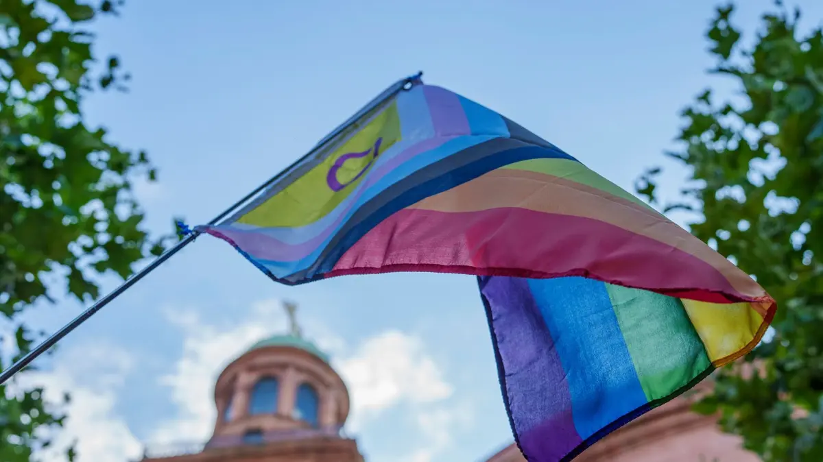 Gedenkkundgebung nach dem Terroranschlag beim Berliner CSD: 27.07.2026, Hessen, Frankfurt am Main: Eine Progress-Regenbogenflagge wird vor der Paulskirche hochgehalten. Auf dem Paulsplatz in Frankfurt findet eine Gedenkkundgebung nach dem Angriff am Rande des CSDs in Berlin statt. Organisiert wurde die Veranstaltung von Bündnis 90/Die Grünen Frankfurt. Foto: Andreas Arnold/dpa +++ dpa-Bildfunk +++