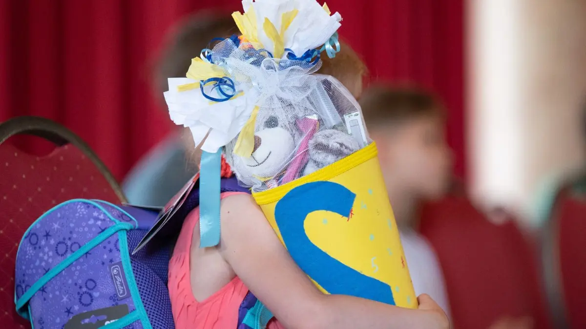 Mädchen hält eine Zuckertüte in den Armen: ARCHIV - In die Schultüte gehören Süßigkeiten, klar. Aber es gibt auch andere kleine Geschenkideen, die Kindern lange Freude machen. (zu dpa: «Nicht nur Süßkram: Was alles in die Schultüte wandern kann») Foto: Sebastian Kahnert/dpa/dpa-tmn - Honorarfrei nur für Bezieher des dpa-Themendienstes +++ dpa-Themendienst +++
