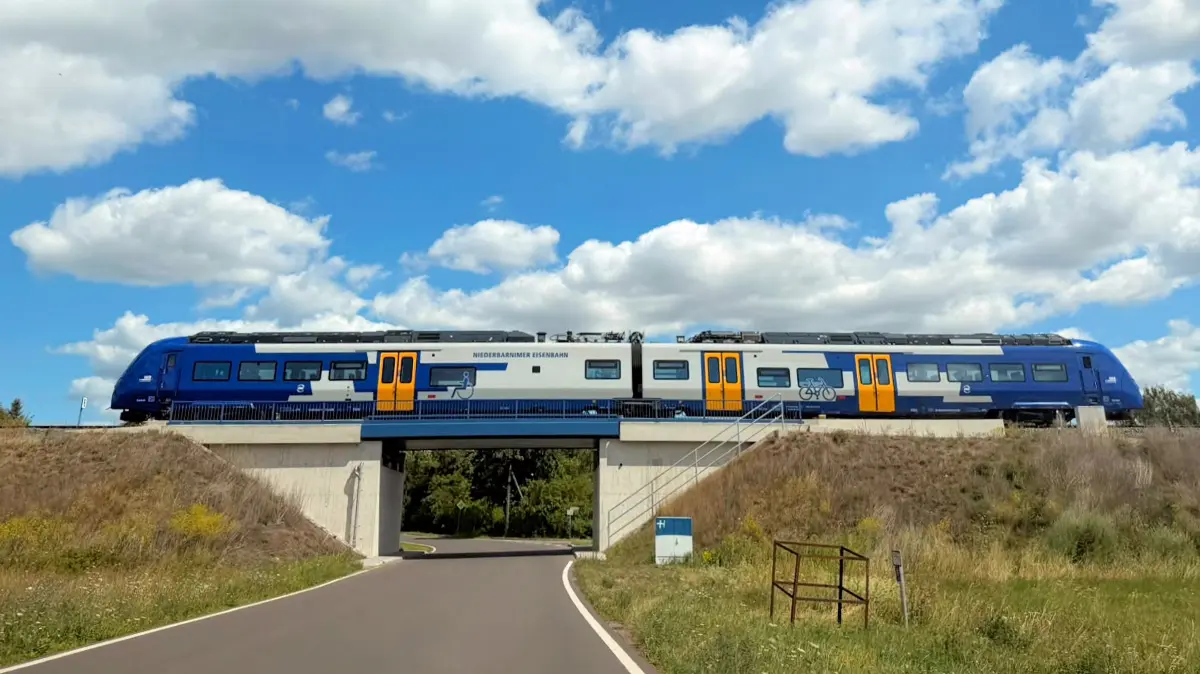 Ein batterieelektrischer Zug der Niederbarnimer Eisenbahn (NEB) überquert eine Brücke über die Werbiger Straße in Neulangsow (bei Seelow). Es handelt sich um die RB60 zwischen Frankfurt/Oder und Eberswalde