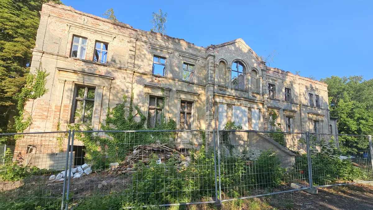 Arbeiten an Kliestows größter Ruine: Die Reste des 2005 abgebrannten Daches des alten Gutshauses sind verschwunden, das Haus wird entkernt - Müllberge hinterm Bauzaun künden vom Entkernen.