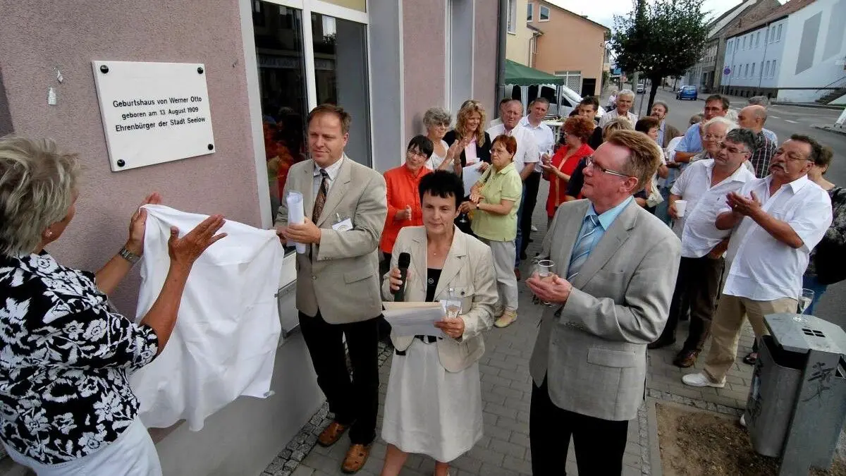 Marmortafel mit schlichter Aufschrift: Bärbel Stellbaum, Michael Schimmel und Marion Krüger (v.l.) vom Heimatverein Schweizerhaus enthüllen mit Bürgermeister Udo Schulz die Tafel am Schuhgeschäft Richter in der Frankfurter Straße 57.