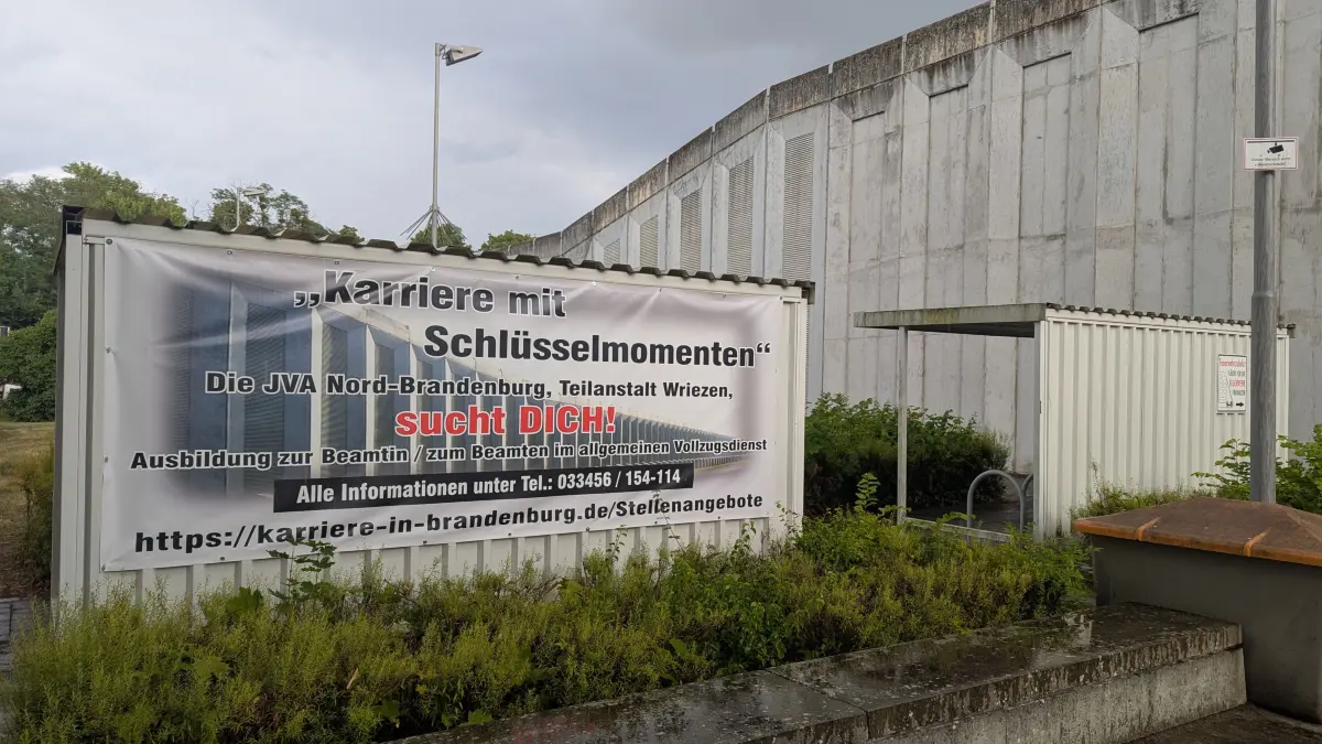 Für die Justizvollzugsanstalt in Wriezen wird Personal gesucht, unter anderem auch mit einem Banner vor dem Gefängnis.