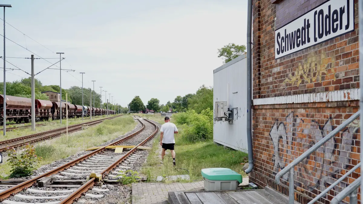 Eine Person läuft vom Bahnübergang Helbigstraße aus vor dem Stellwerk durch den Gleisbereich und anschließend entlang des Gleises in Richtung Bahnhof Schwedt (nachgestellte Szene).