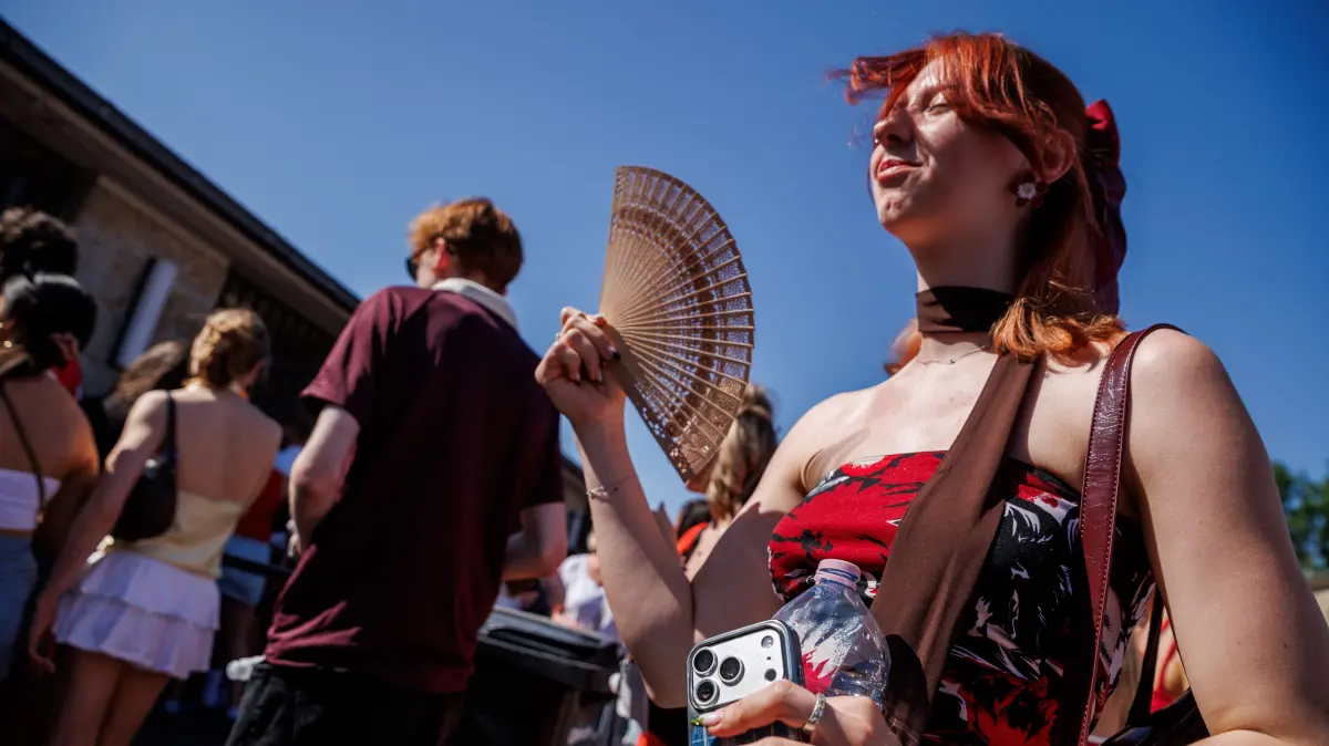 Eine junge Frau hält auf dem Weg zum Konzert des US-amerikanischen Musikers Bruno Mars im Olympiastadion zur Kühlung einen Fächer in der Hand. Derzeit rollt eine Hitzewelle über Brandenburg und Berlin. +++ dpa-Bildfunk +++