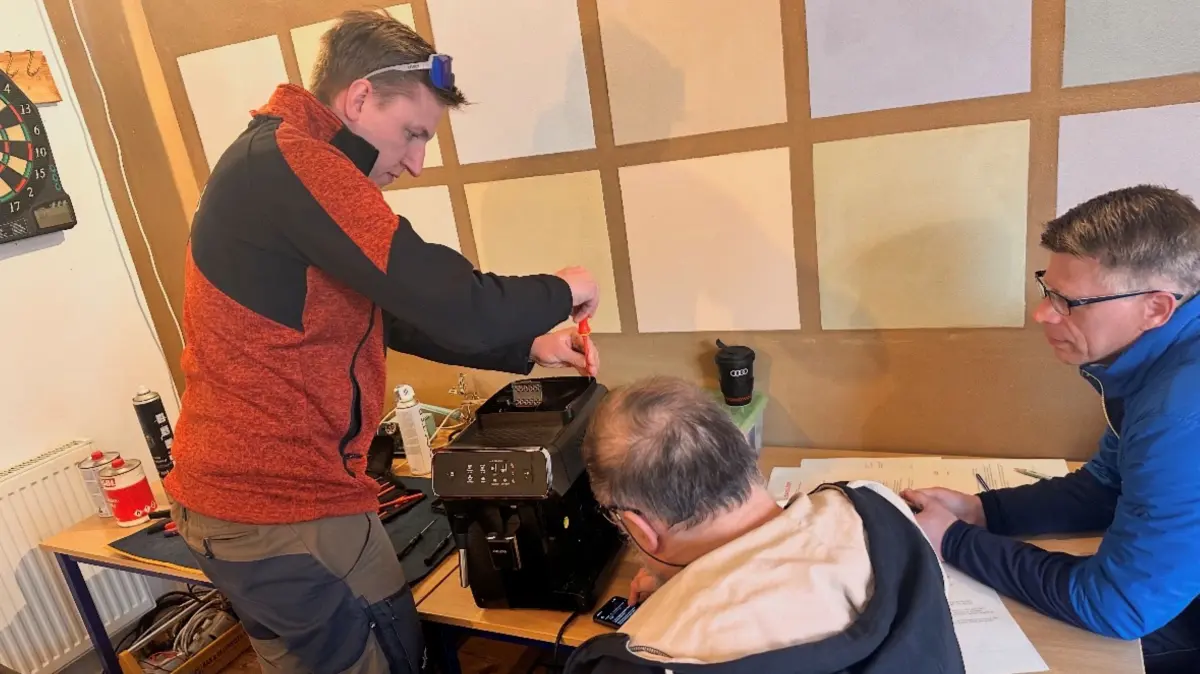 Björn Wudka legt im Repair-Café Neuenhagen Hand an einen defekten Kaffeeautomaten an. Die Besucher verfolgen jeden Handgriff und hoffen, dass das Gerät bald wieder seiner eigentlichen Funktion gerecht wird.