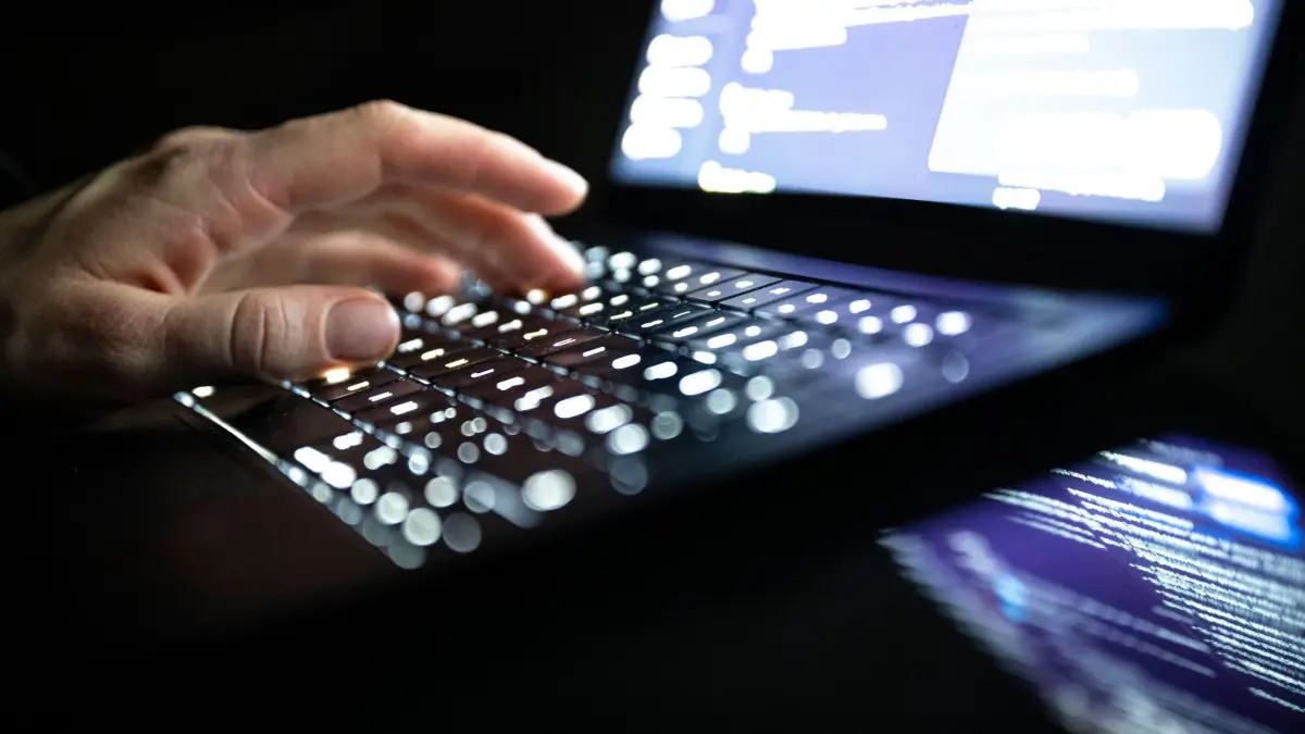 Cyberkriminalität: ILLUSTRATION - 14.12.2025, NA, Berlin: Eine Person tippt mit den Fingern auf einer beleuchteten Laptop-Tastatur. (gestellte Szene) (zu dpa: «Hackerangriff auf Berliner Landesnetz - Ausmaß unbekannt») Foto: Philip Dulian/dpa +++ dpa-Bildfunk +++