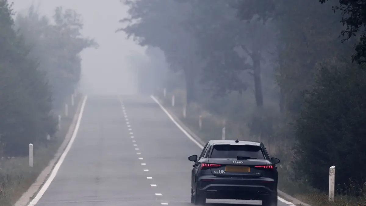 Waldbrand im Hohen Venn: 18.08.2026, Belgien, Eupen: Ein Auto fährt über die Monschauer Landstraße in Richtung Eupen. Die Straße führt durch das Hohe Venn und Rauchschwaden aus dem Brandgebiet ziehen darüber hinweg. Im belgischen Naturschutzgebiet Hohes Venn dauert der Kampf gegen die Flächenbrände an. Beteiligt sind auch deutsche Einsatzkräfte, die von der Eifelstadt Monschau aus agieren. Foto: Oliver Berg/dpa +++ dpa-Bildfunk +++